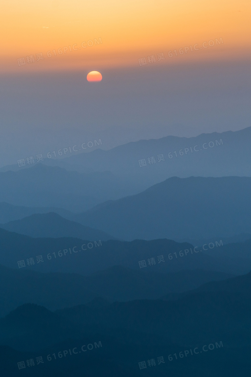 一轮红日与隐约可见的山峦高清图片