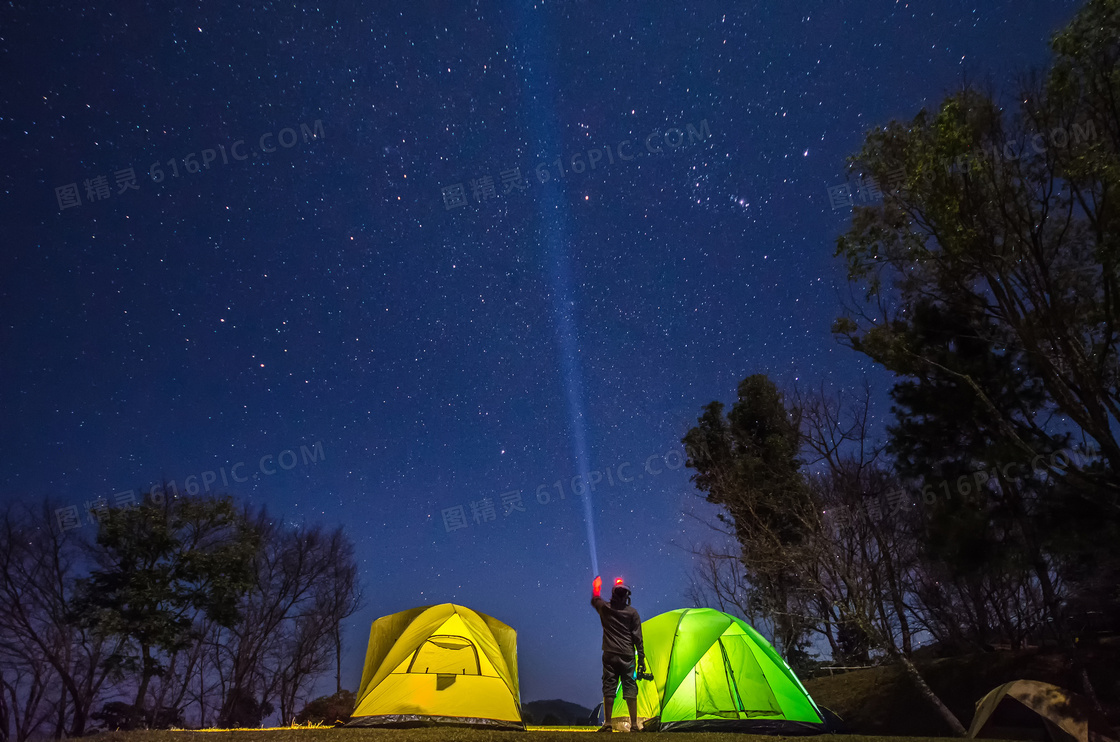用探照灯照向夜空的露营者高清图片