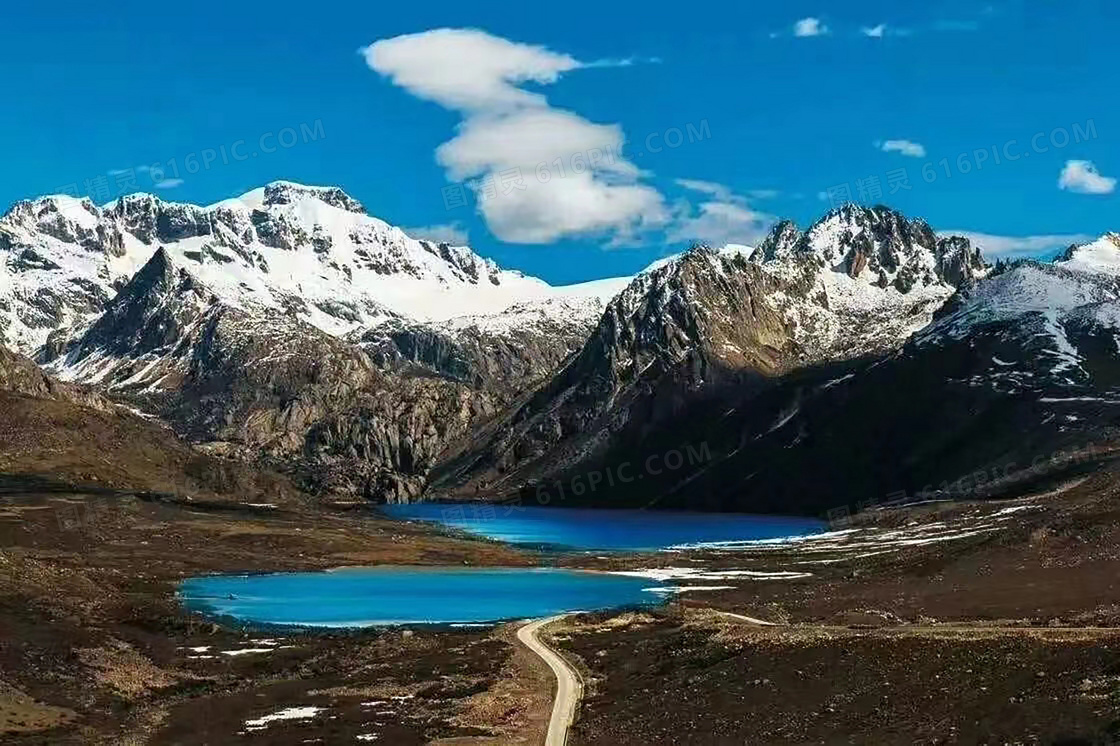 雪山脚下的湖泊和道路摄影图片