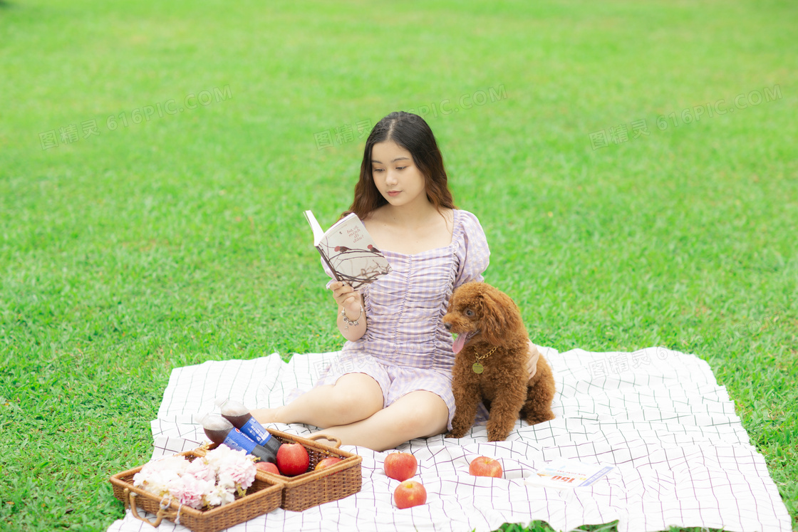 草地狗狗陪美女看书图片