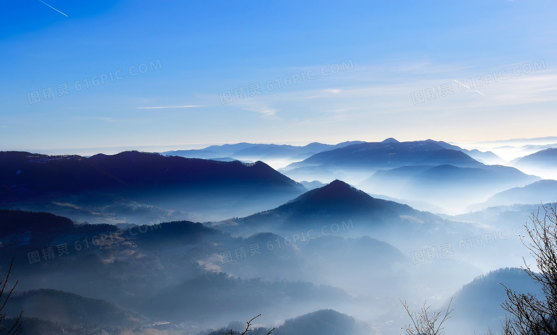 蓝天下云雾缭绕的山峰摄影图片