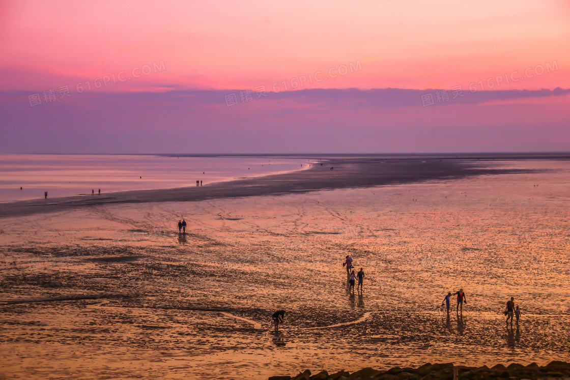 黄昏傍晚滩涂上的人群摄影高清图片