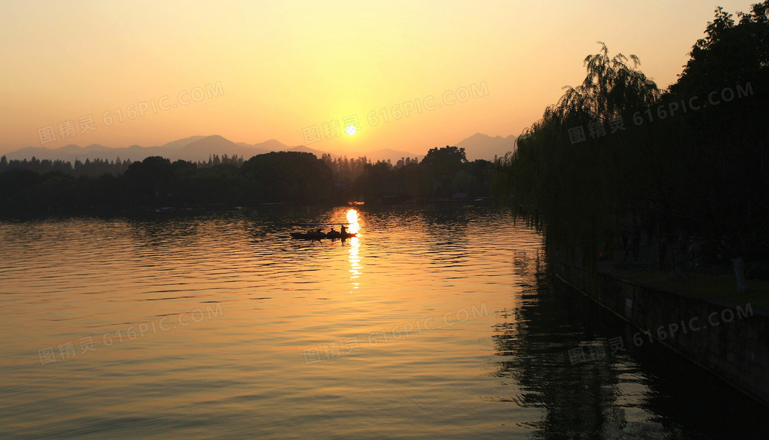 夕阳下湖泊中的手划船摄影图片