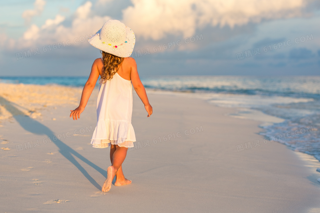 漫步在沙滩上的吊带小女孩高清图片