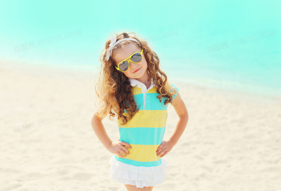 沙滩上叉着腰的卷发小女孩高清图片