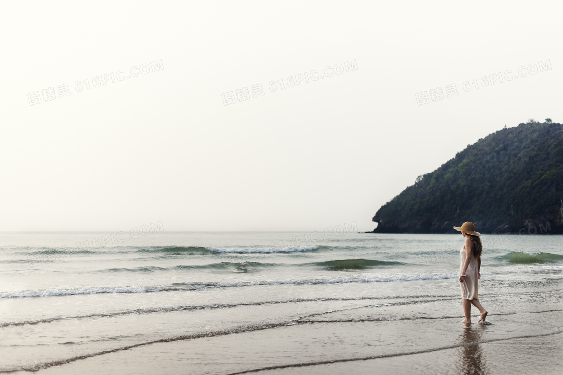 正漫步在海边浅水区的美女高清图片