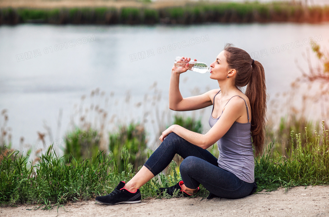 坐在河邊休息喝水的運動裝美女圖片