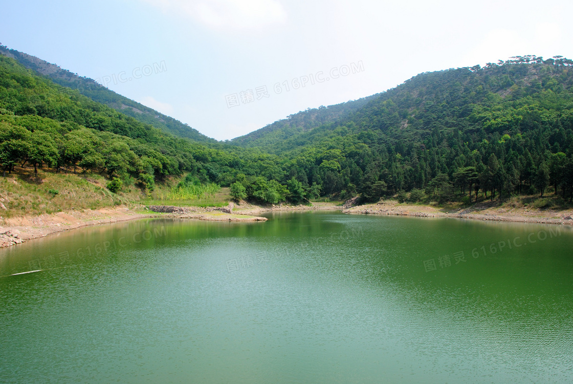 绿色山坡下的湖泊摄影图片